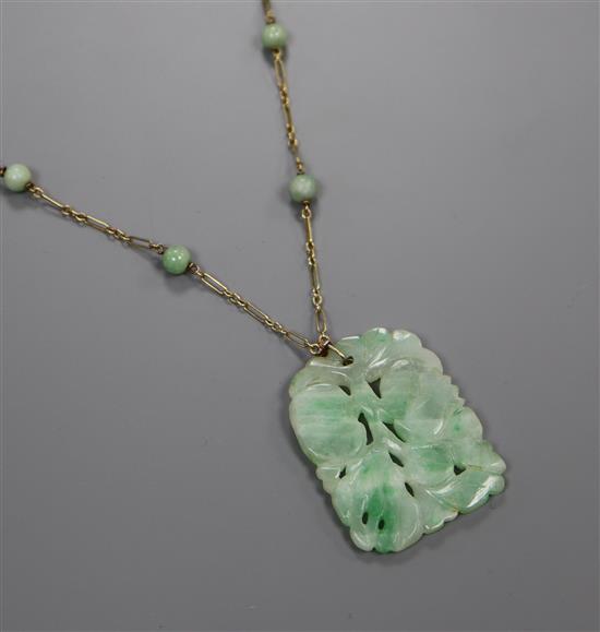 A 14k yellow metal and carved jadeite set pendant necklace, pendant 40mm.